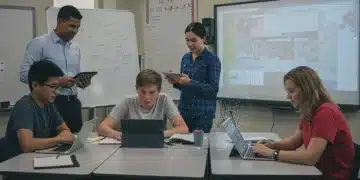 Students and educators using digital devices in a modern classroom for digital literacy skills development.